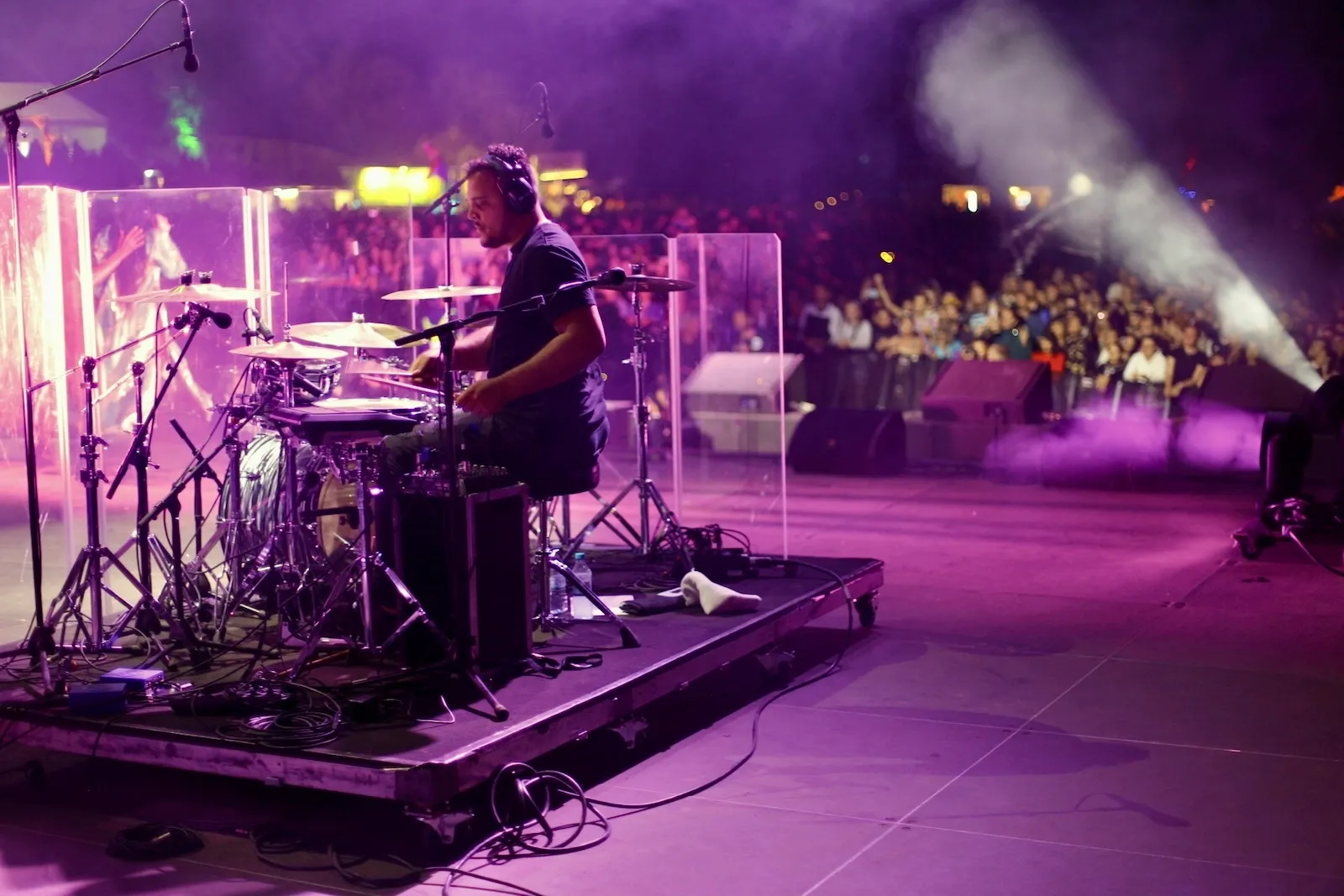 Anthony met koptelefoon achter de drums op Melt Festival in Duitsland, paars podiumlicht en publiek rechts